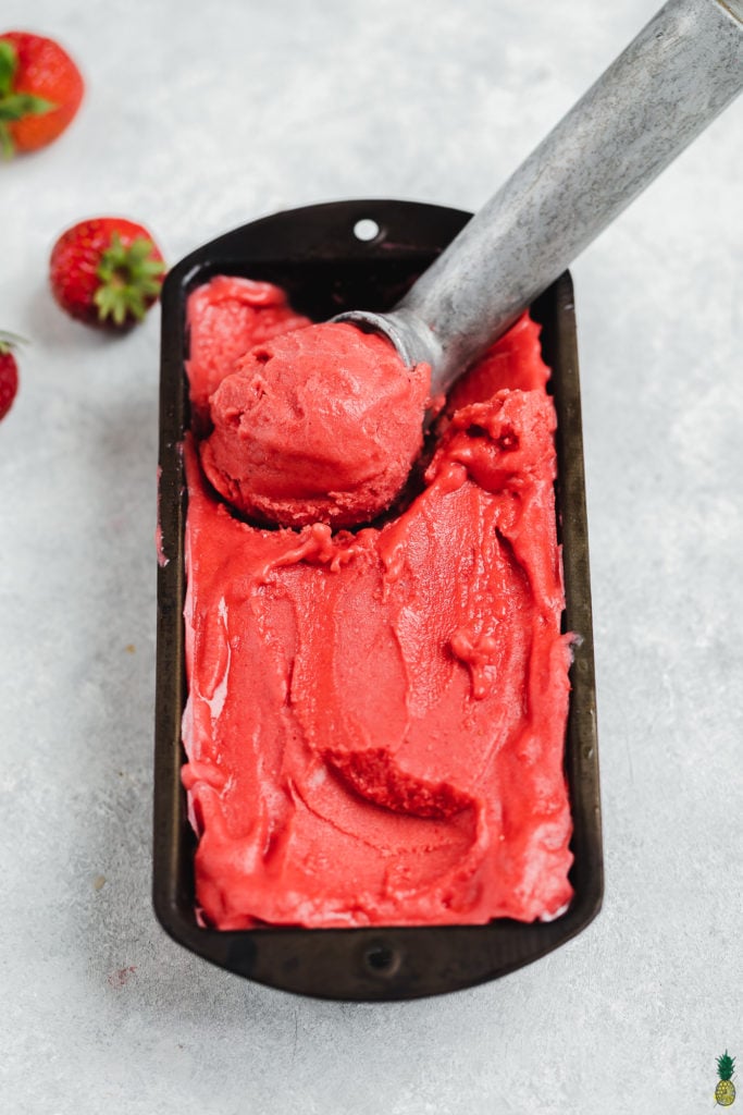 scooping homemade strawberry frozen yogurt by sweet simple vegan