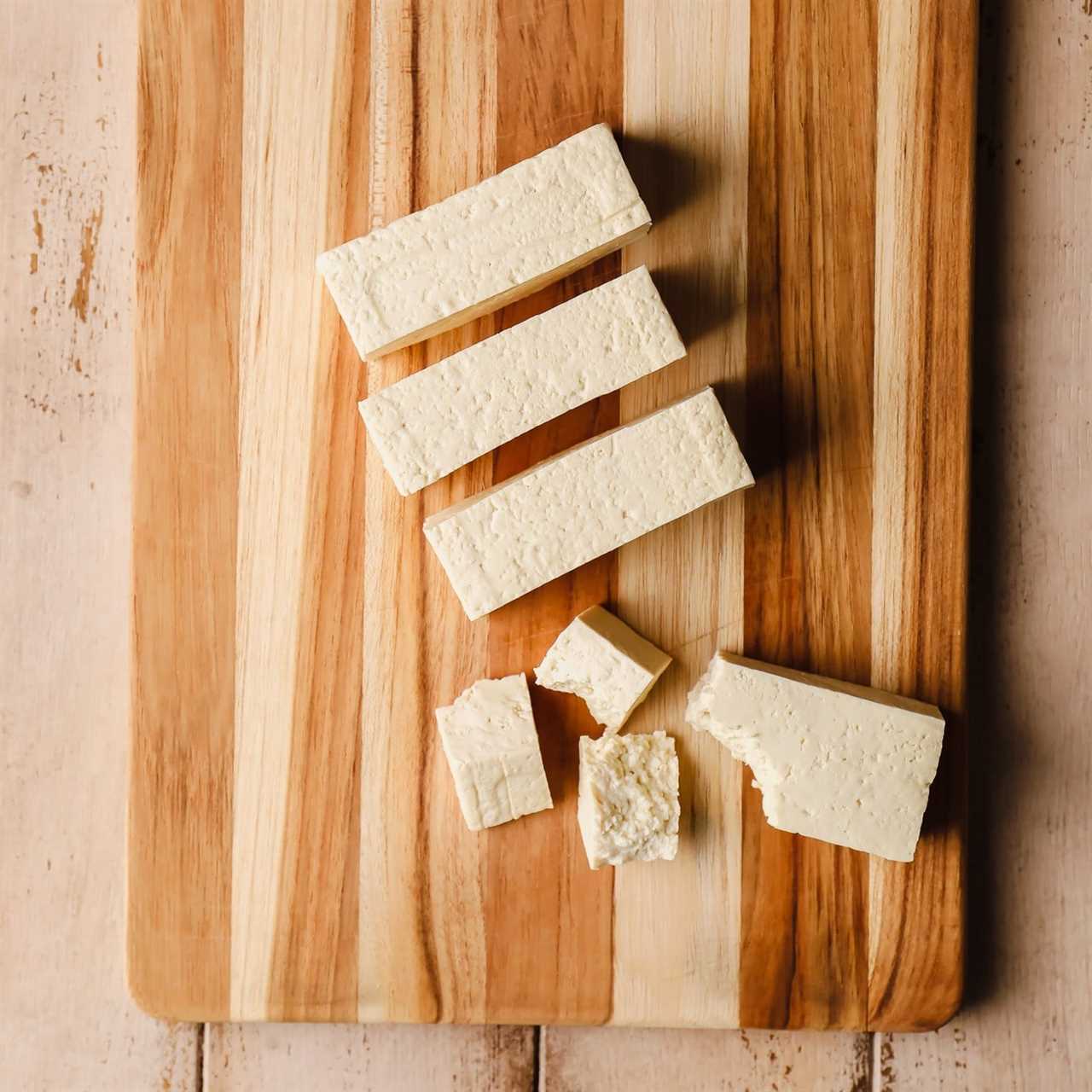 ripping a sliced tofu block into smaller pieces.