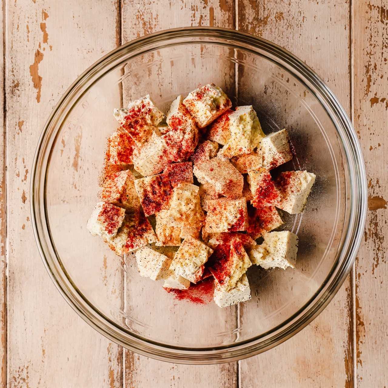 tofu pieces covered in seasonings in a glass bowl.