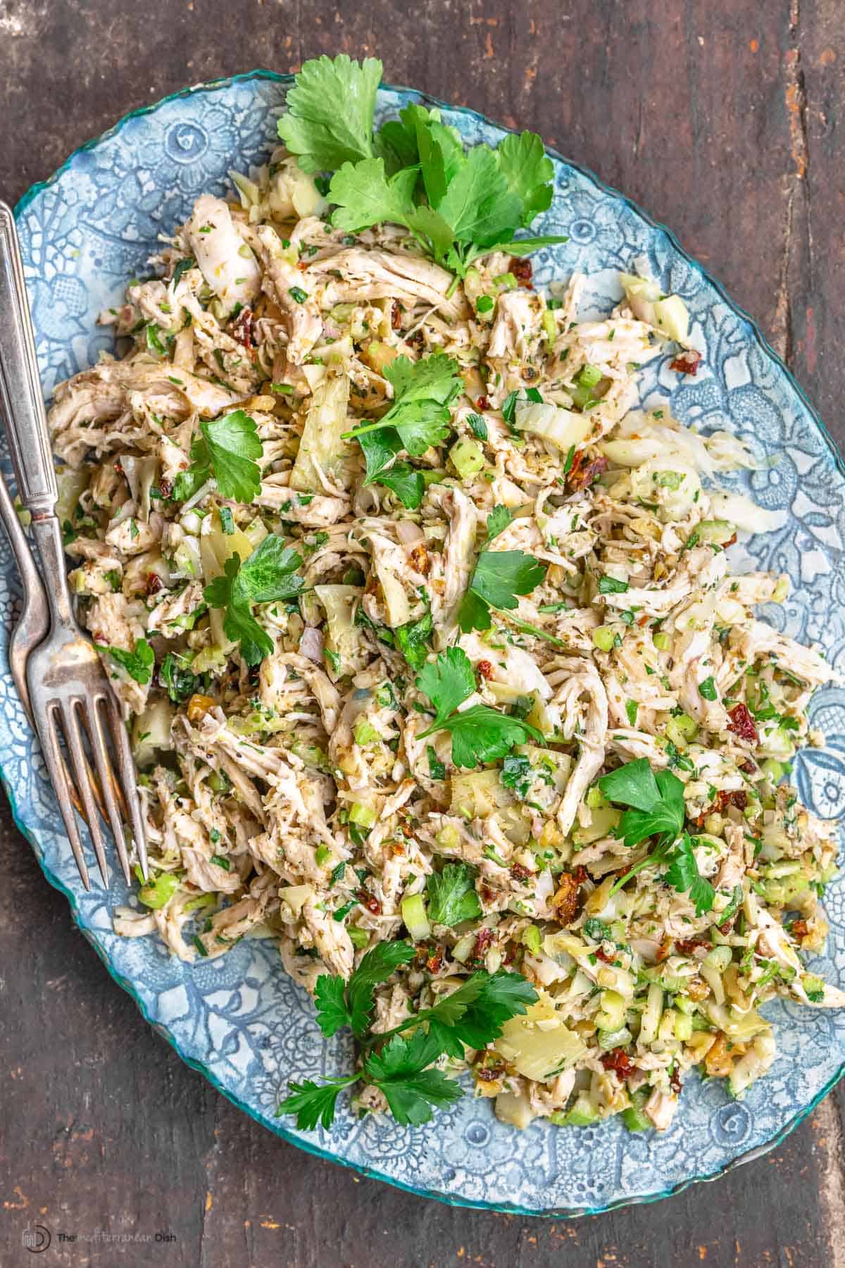 chicken salad on a platter, garnished with parsley, with a fork for serving