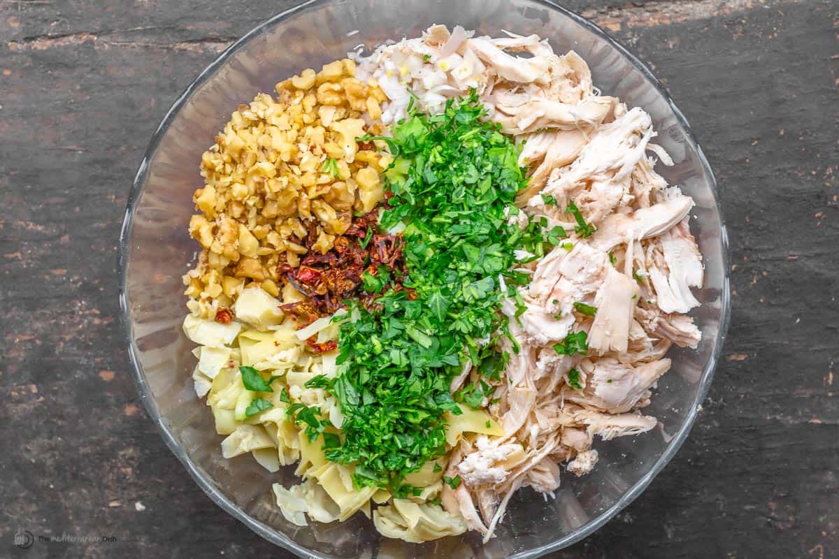 chicken, vegetables, herbs, and walnuts, arranged in a bowl