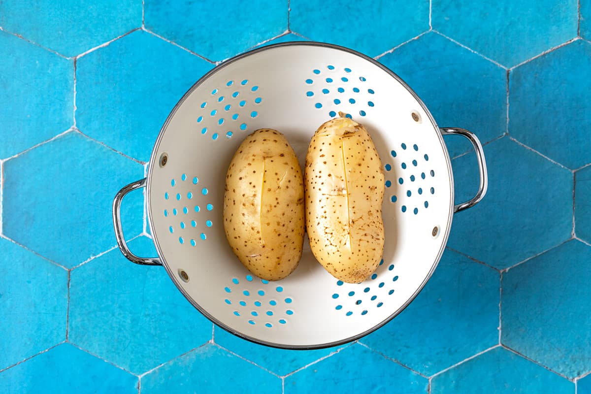 Colander with two cooked potatoes for potato gnocchi.