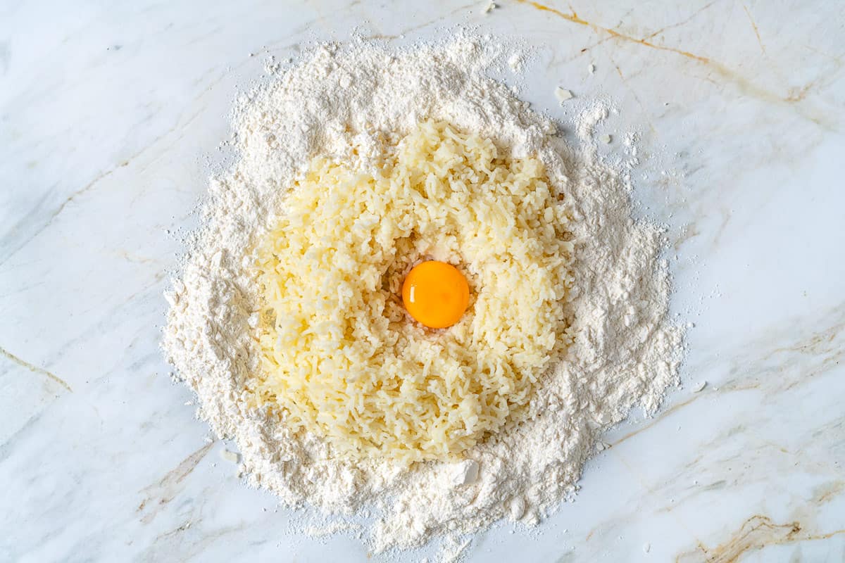 Riced potatoes surrounded by all purpose flour with an egg yolk in the middle.