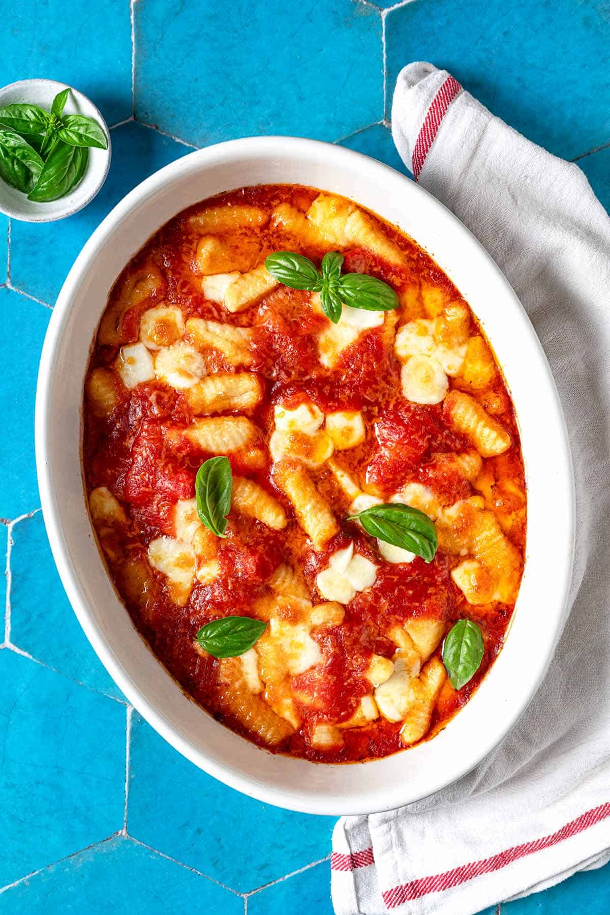 Baked gnocchi alla sorrentina with a garnish of fresh basil leaves.