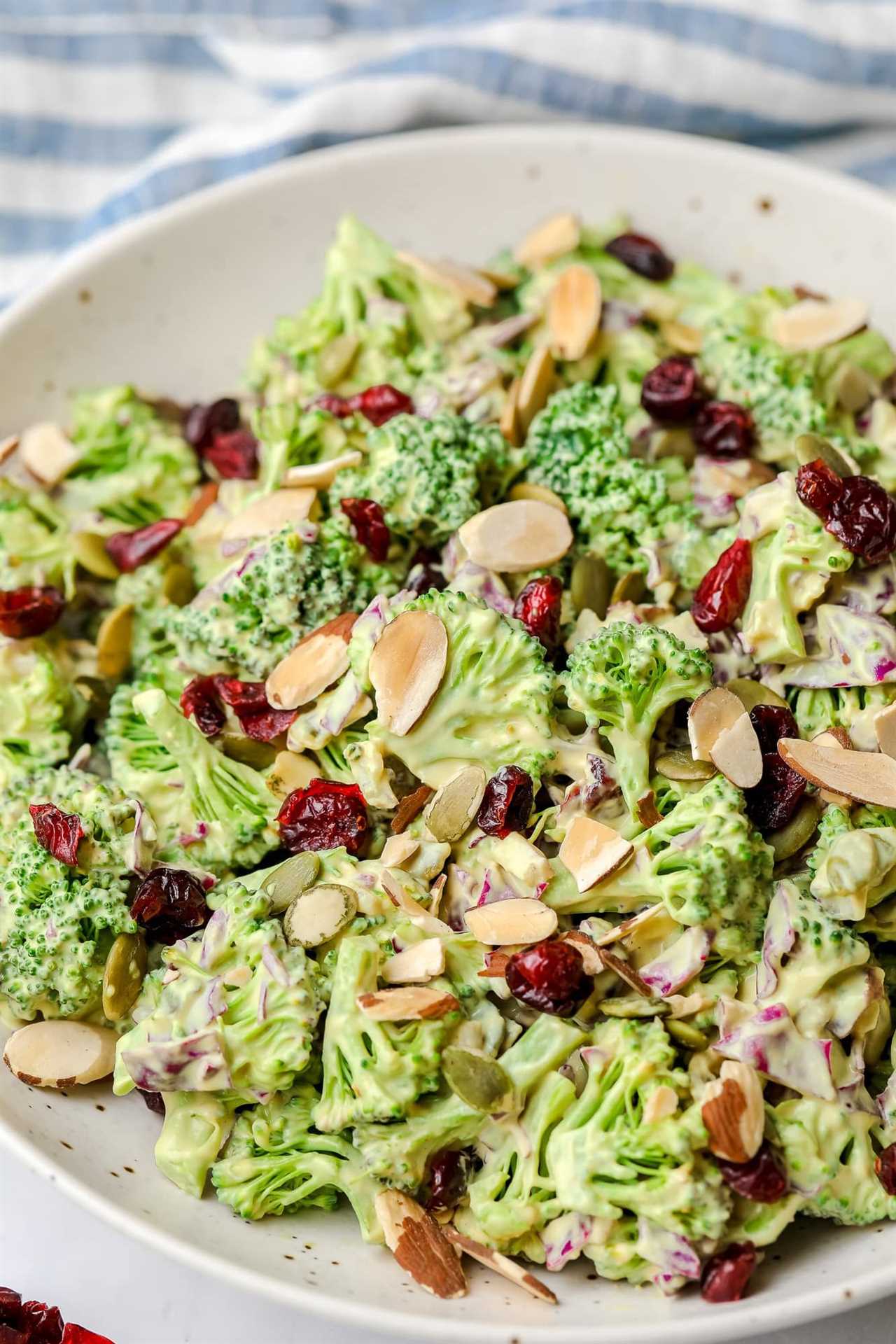 vegan broccoli salad tossed in creamy dressing and topped with almonds in a large white bowl.