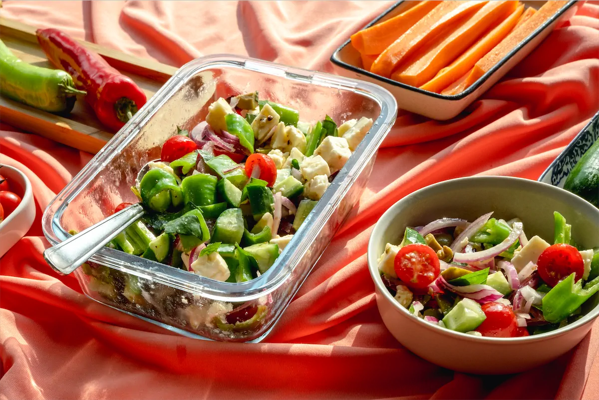 A bowl of keto salad next to a glass serving dish full of salad.