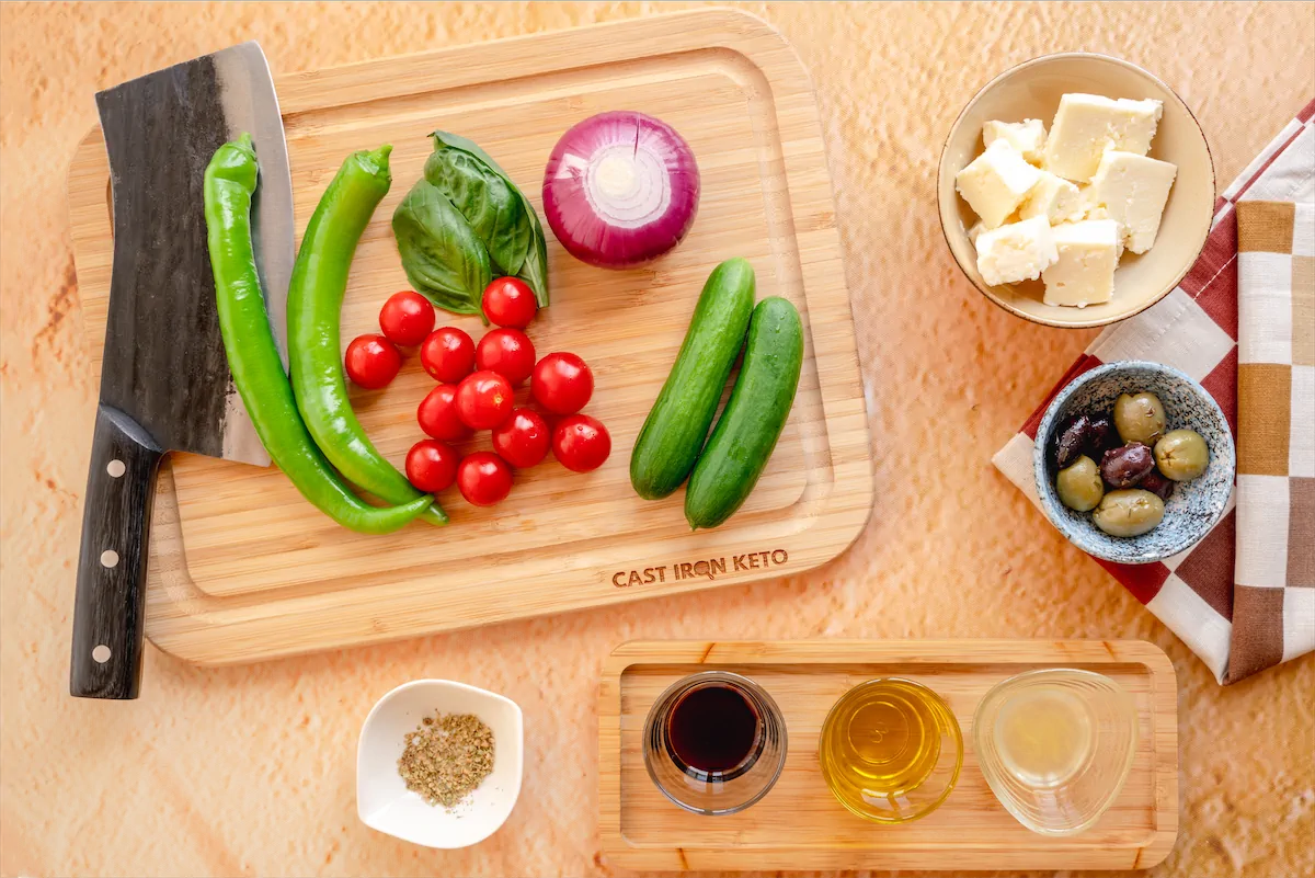 Cherry tomatoes, Persian cucumber, olives, sweet green pepper, red onion, feta cheese, red wine vinegar, tablespoon extra virgin olive oil, dried oregano, lemon juice, made ready on the kitchen table.