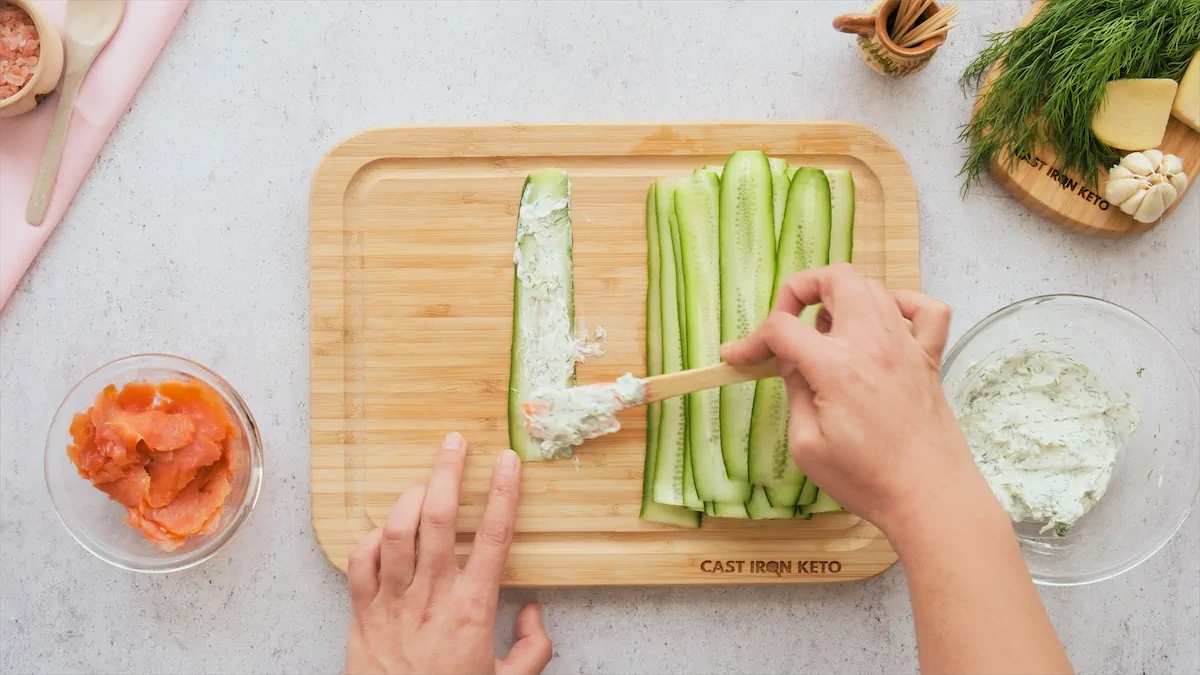 Labneh mixture being spread on a cucumber slice.