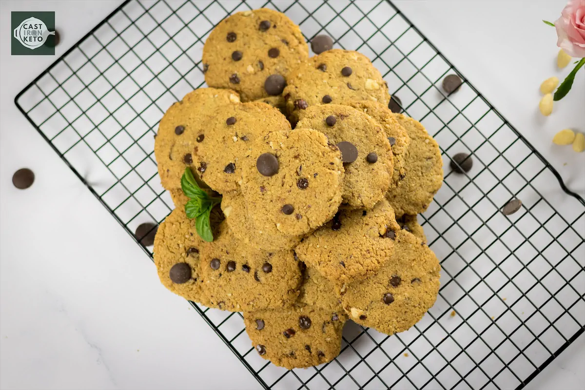 Chocolate chip cookies placed on cooling rack on kitchen table.