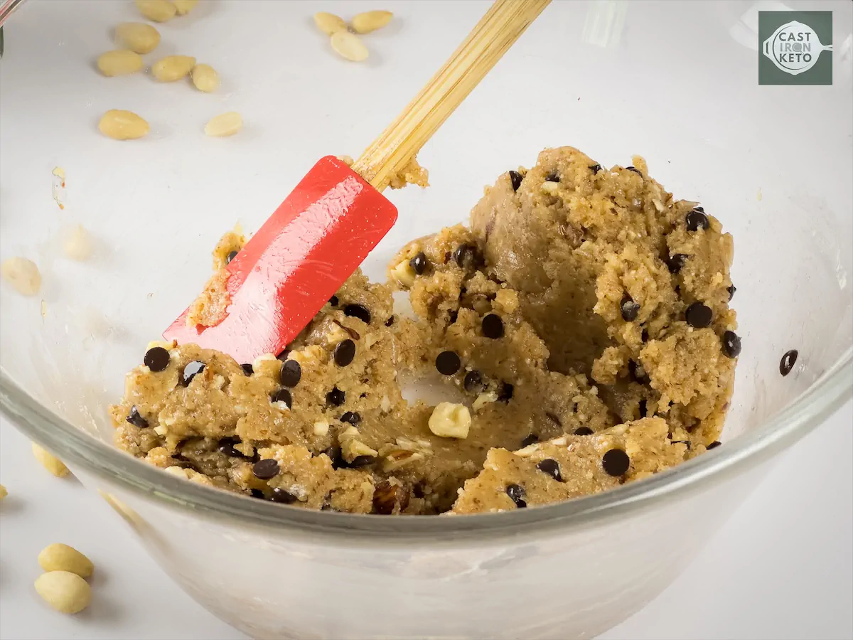 Mixing the chocolate chips and chopped walnut with the cookie dough using spatula.