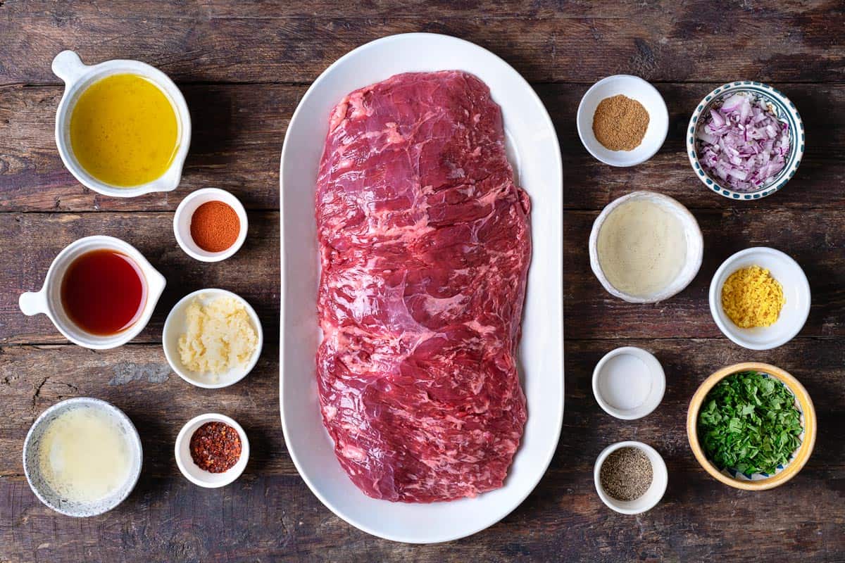 ingredients for grilled skirt steak including skirt steak, salt, pepper, shallots, garlic, parsley, cumin, aleppo pepper, paprika, lemon zest, lemon juice, red wine vinegar, and olive oil.