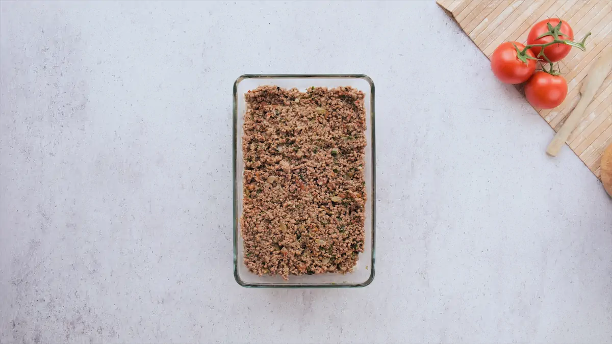 Ground beef and sliced eggplants mixed together in a baking dish to bake.