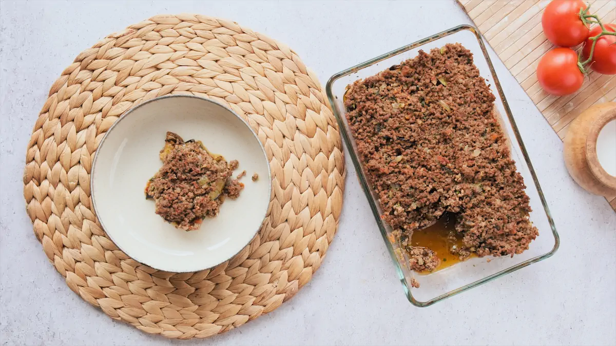 Keto Moussaka recipe served in a plate from a baking dish full of it.