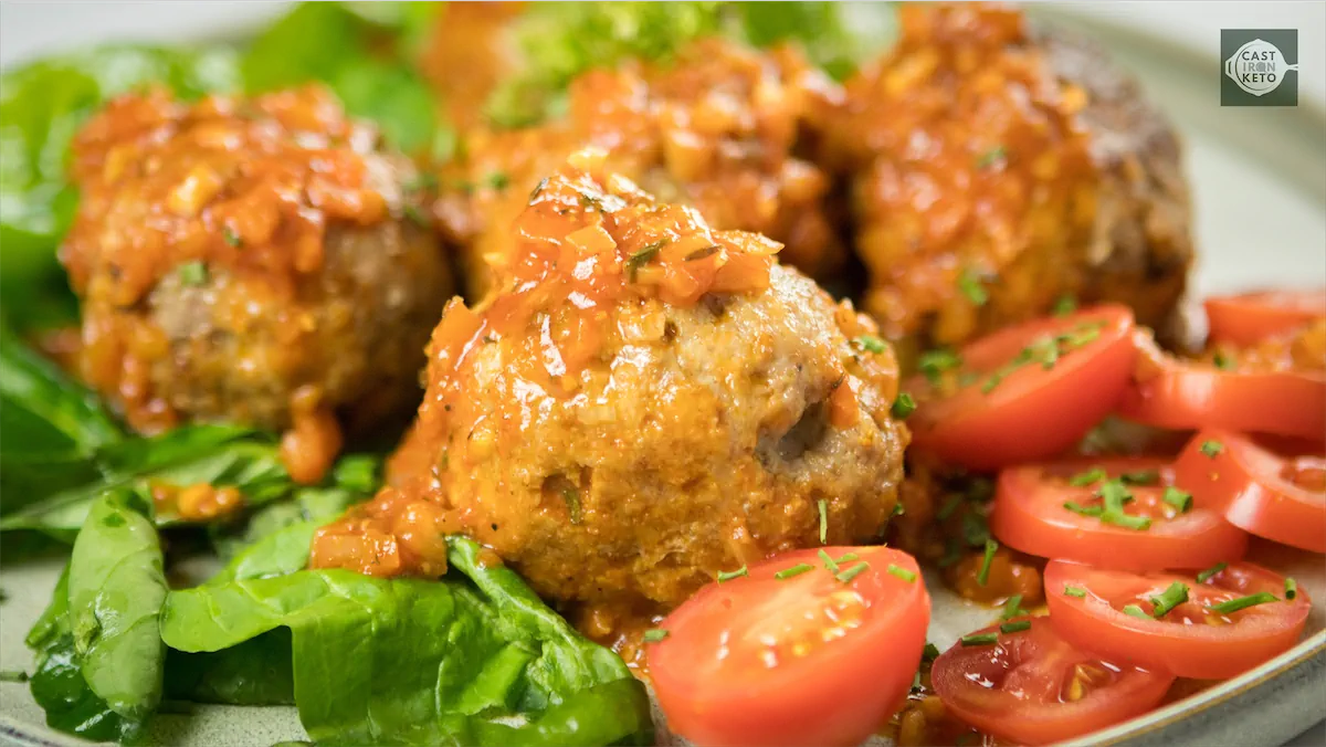 Authentic keto Italian meatballs recipe served on a plate along with sliced tomatoes.