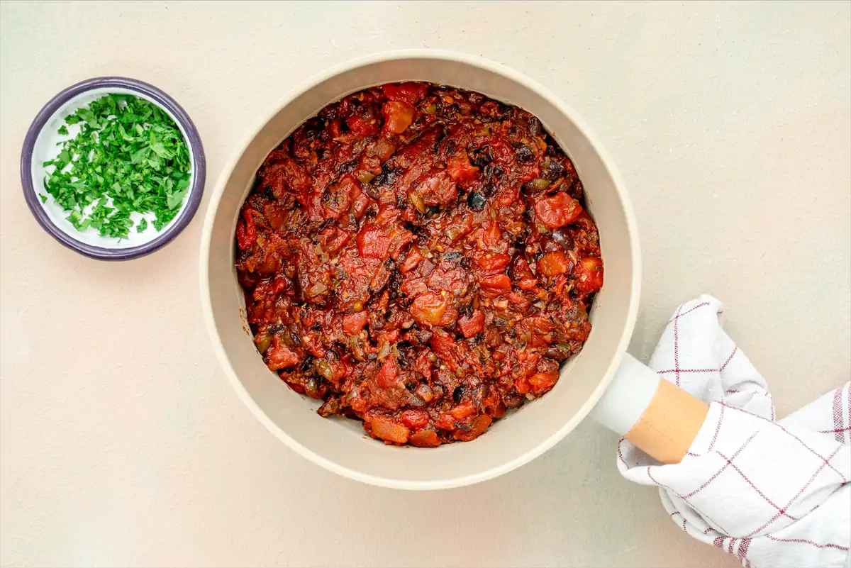 Puttanesca sauce recipe placed in a pan on kitchen table.