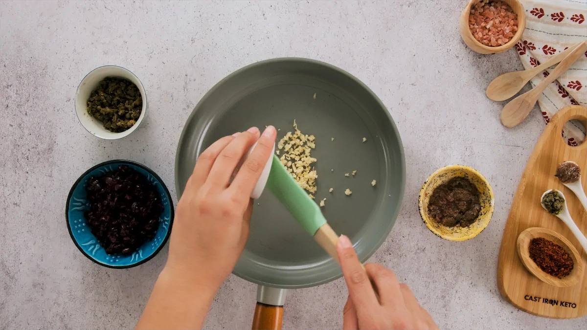 Adding minced garlic in a skillet.