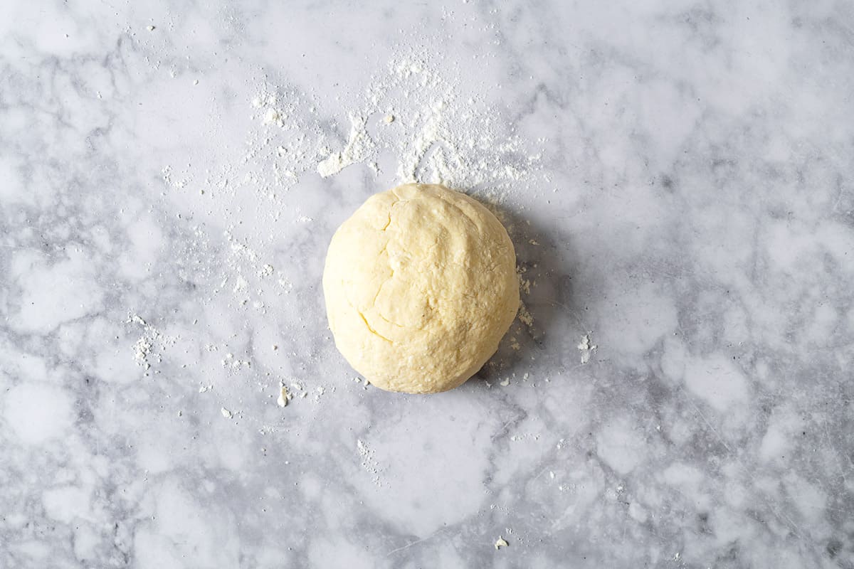 a ball of dough on a countertop sprinkled with flour.