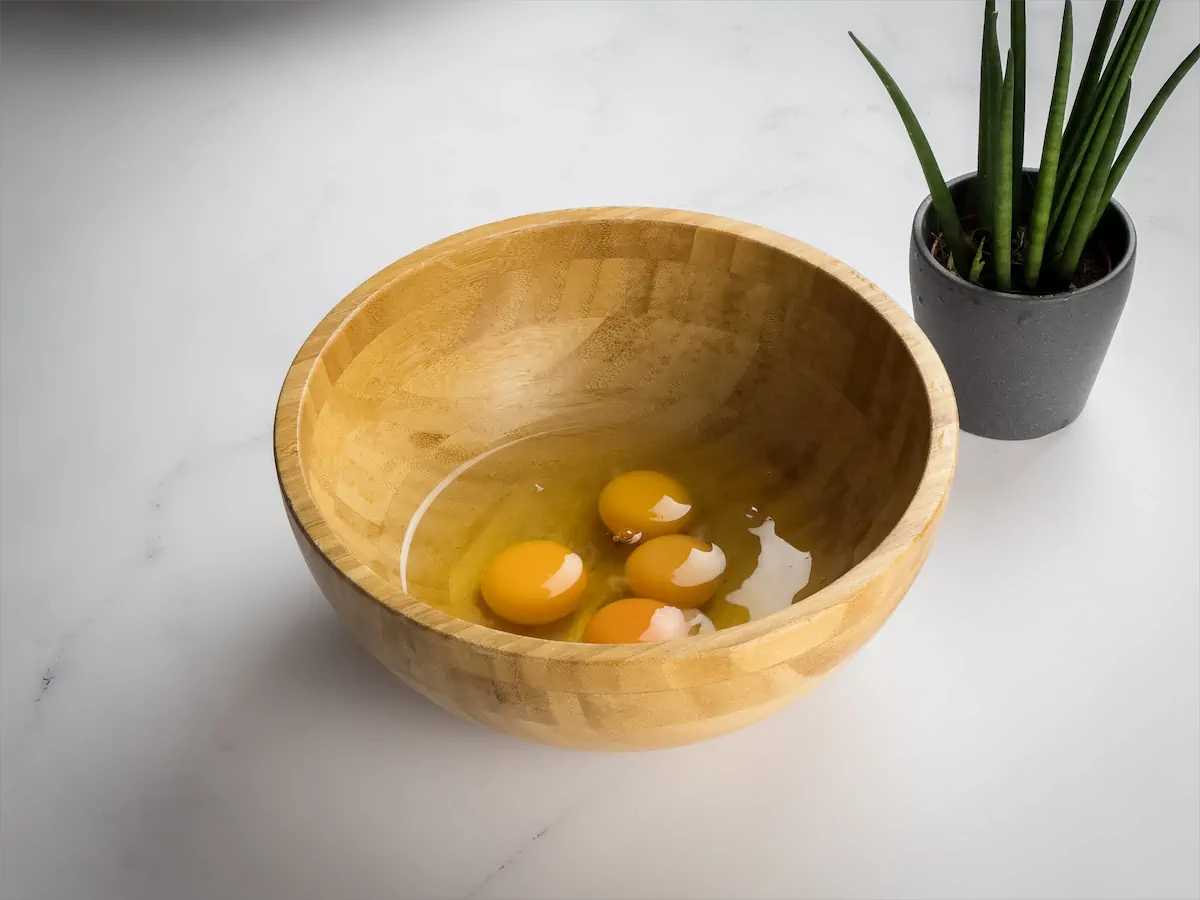 Four large eggs are cracked and kept in a big bowl.
