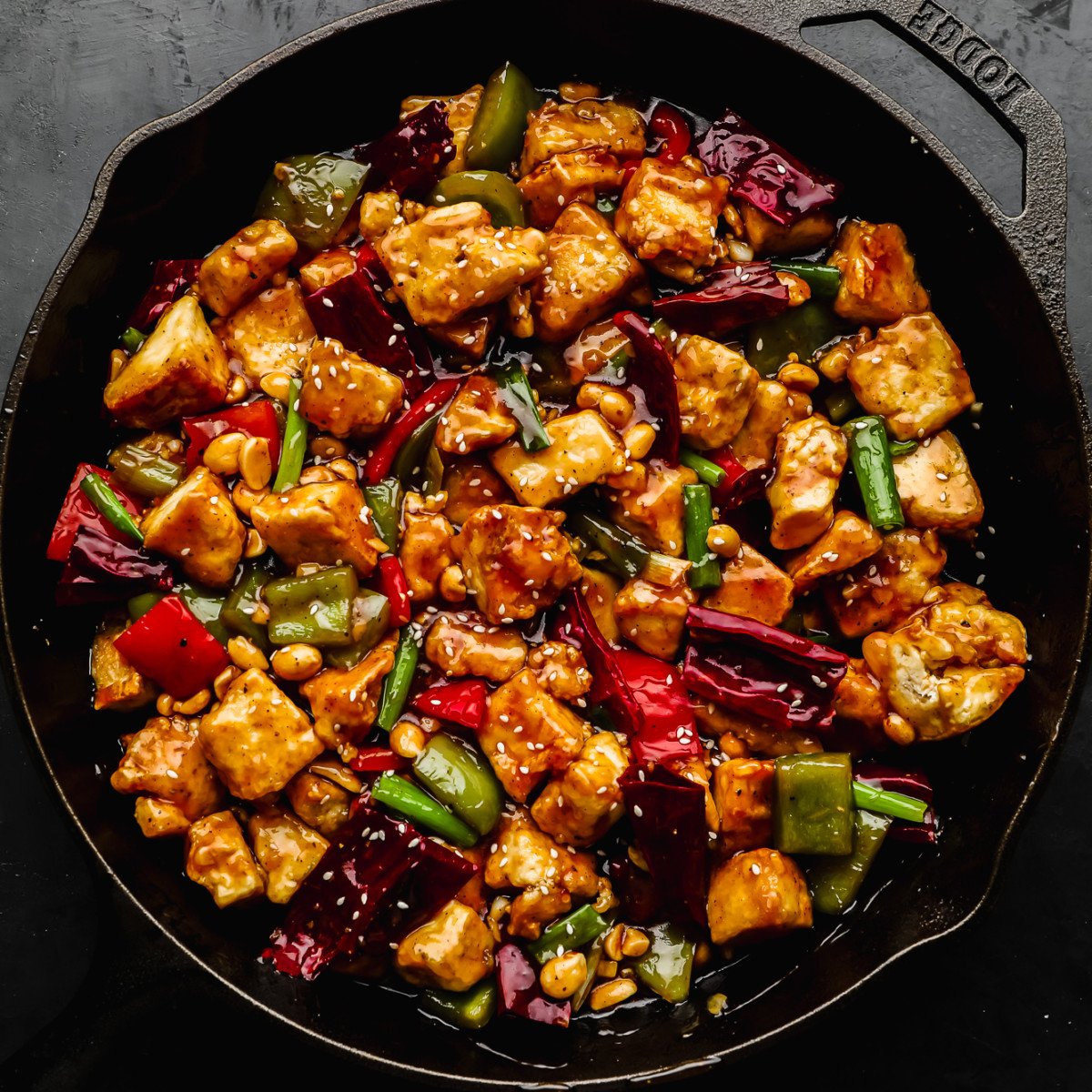 cooked kung pao tofu and vegetables in a large black cast iron skillet.
