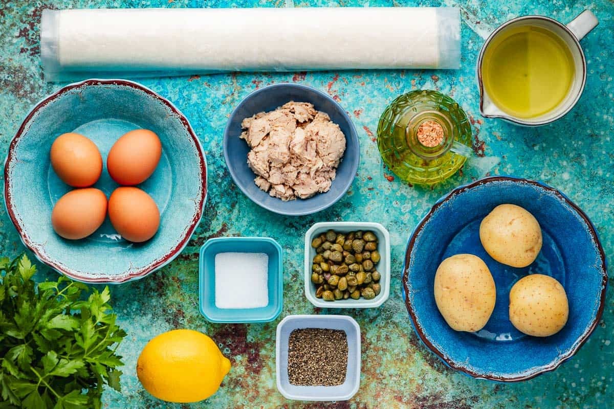 ingredients for brik including filo dough, potatoes, salt, pepper, oil, parsley, tuna, capers, and lemon.