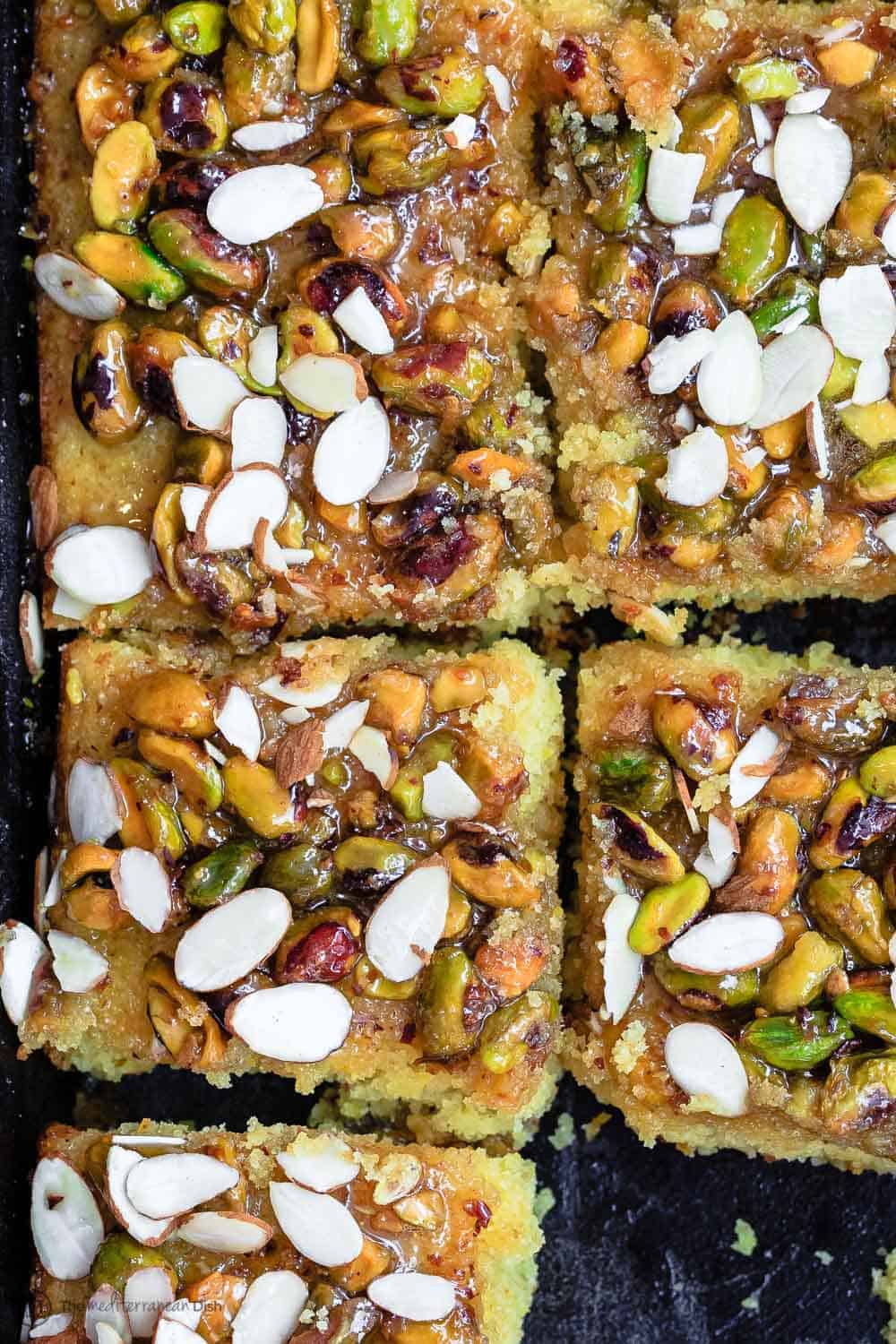 Close-up of slices of Greek Honey Orange Cake garnished with pistachios and almonds.