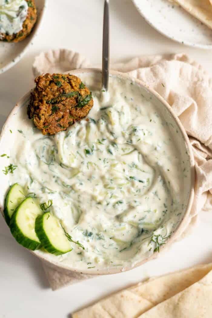 vegan tzatziki sauce in a bowl with cucumber and falafel garnish