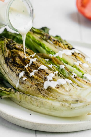 ranch dressing being poured onto grilled romaine lettuce