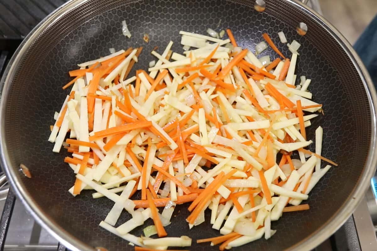 step by step - sweet potato being added to carrots, onion, and garlic