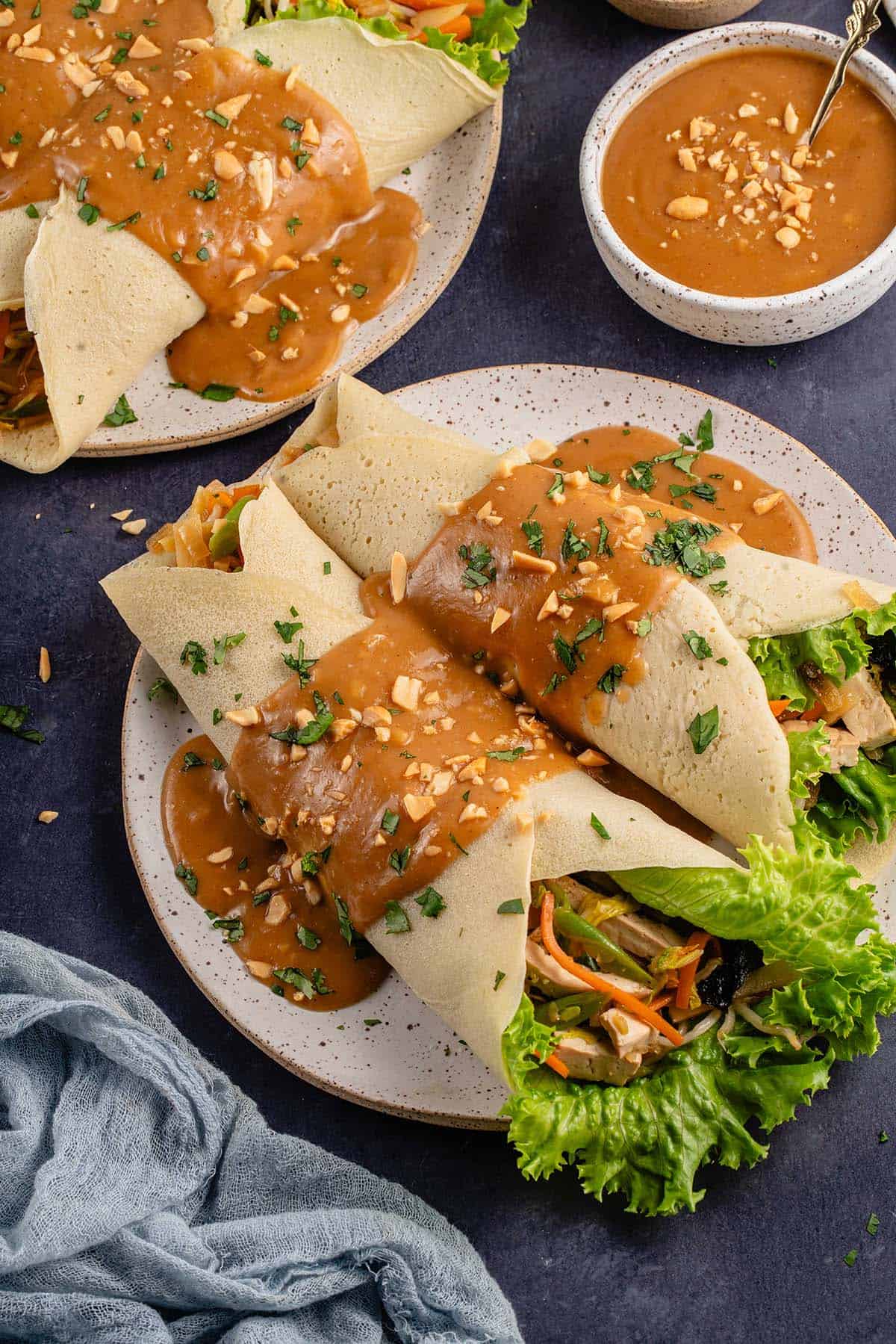 lumpiang sariwa covered in peanut sauce on a plate