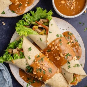 lumpiang sariwa covered in peanut sauce on a plate