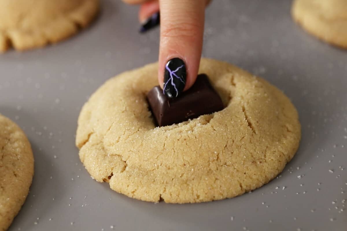 chocolate being added to the finished peanut butter blossom cookies