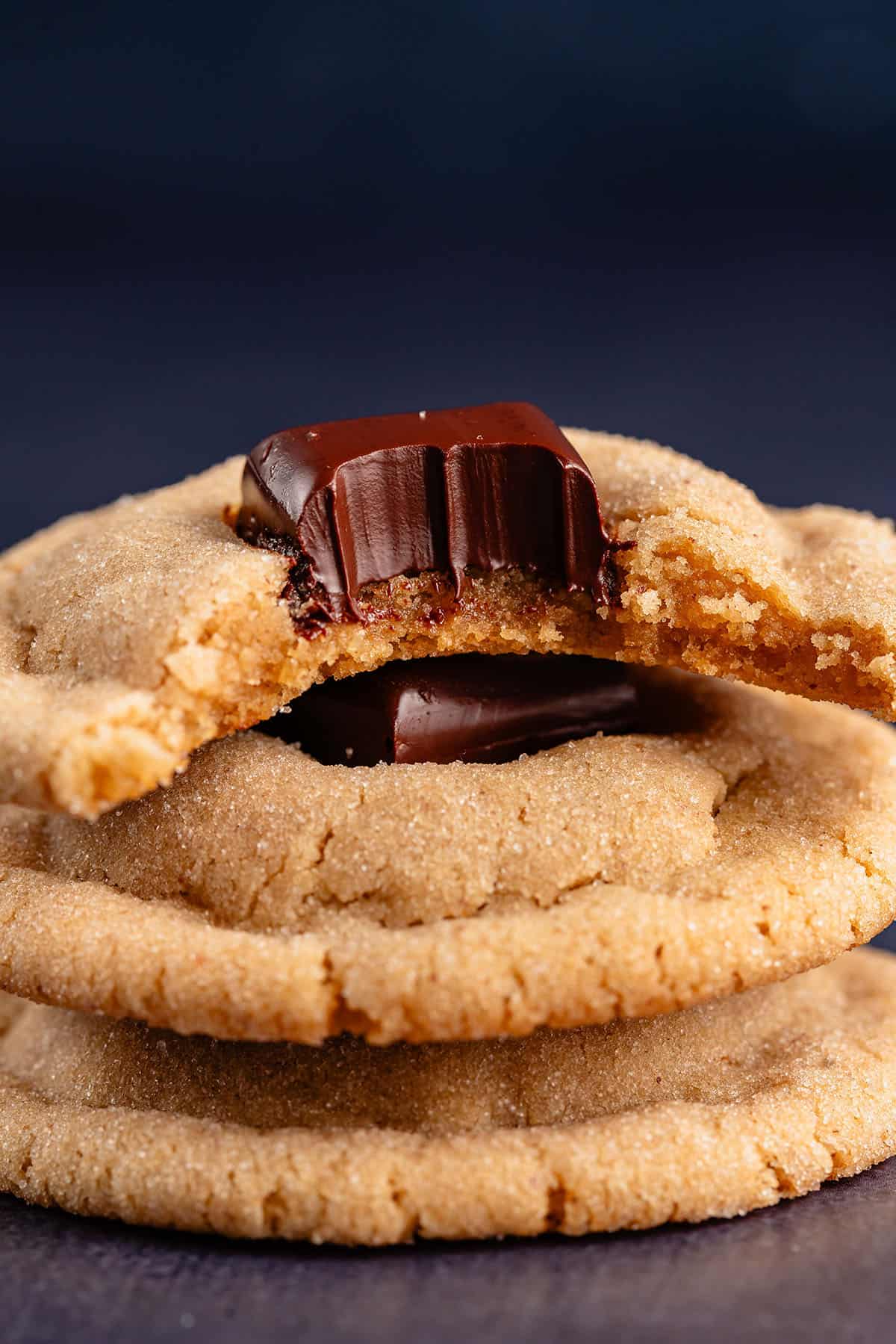 peanut butter blossom cookies stacked with a bite taken out of the top one