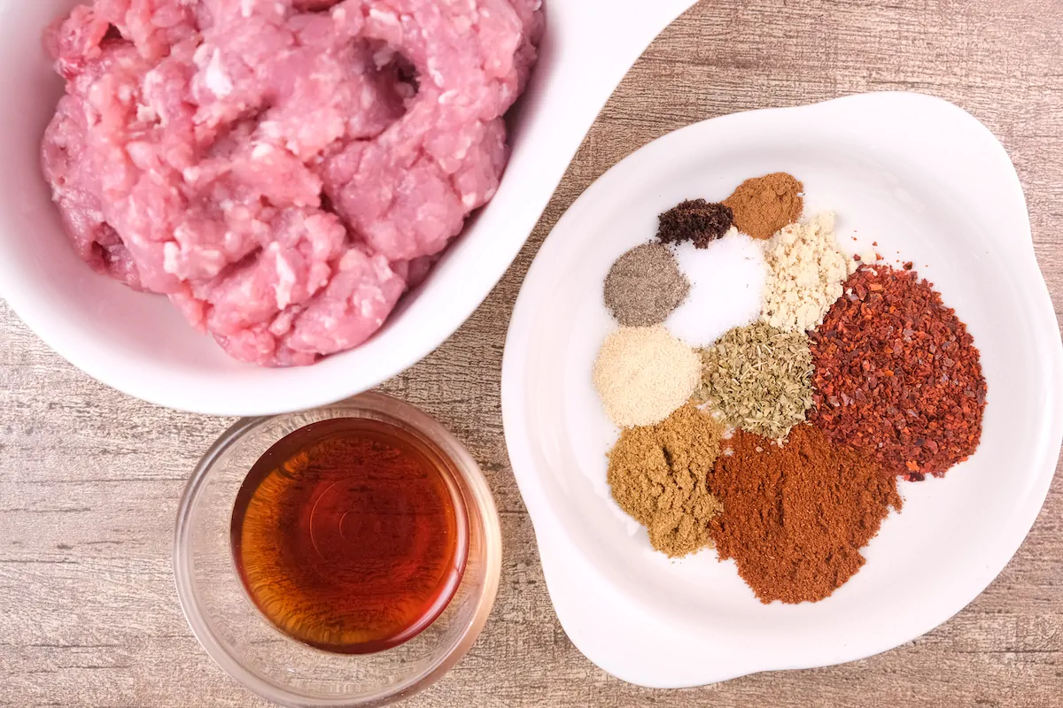 Ground pork, spices and red wine vinegar gathered and measured on the table.