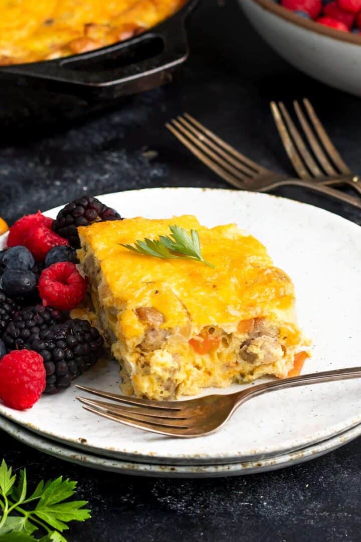 Keto Breakfast Casserole on a white plate with a fork and a mixture of berries