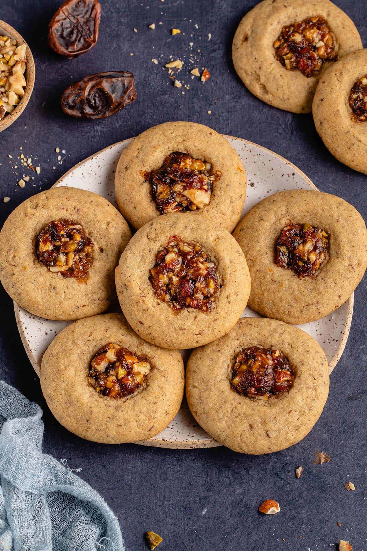 vegan baklava cookies on a plate with dates and nuts on blue background