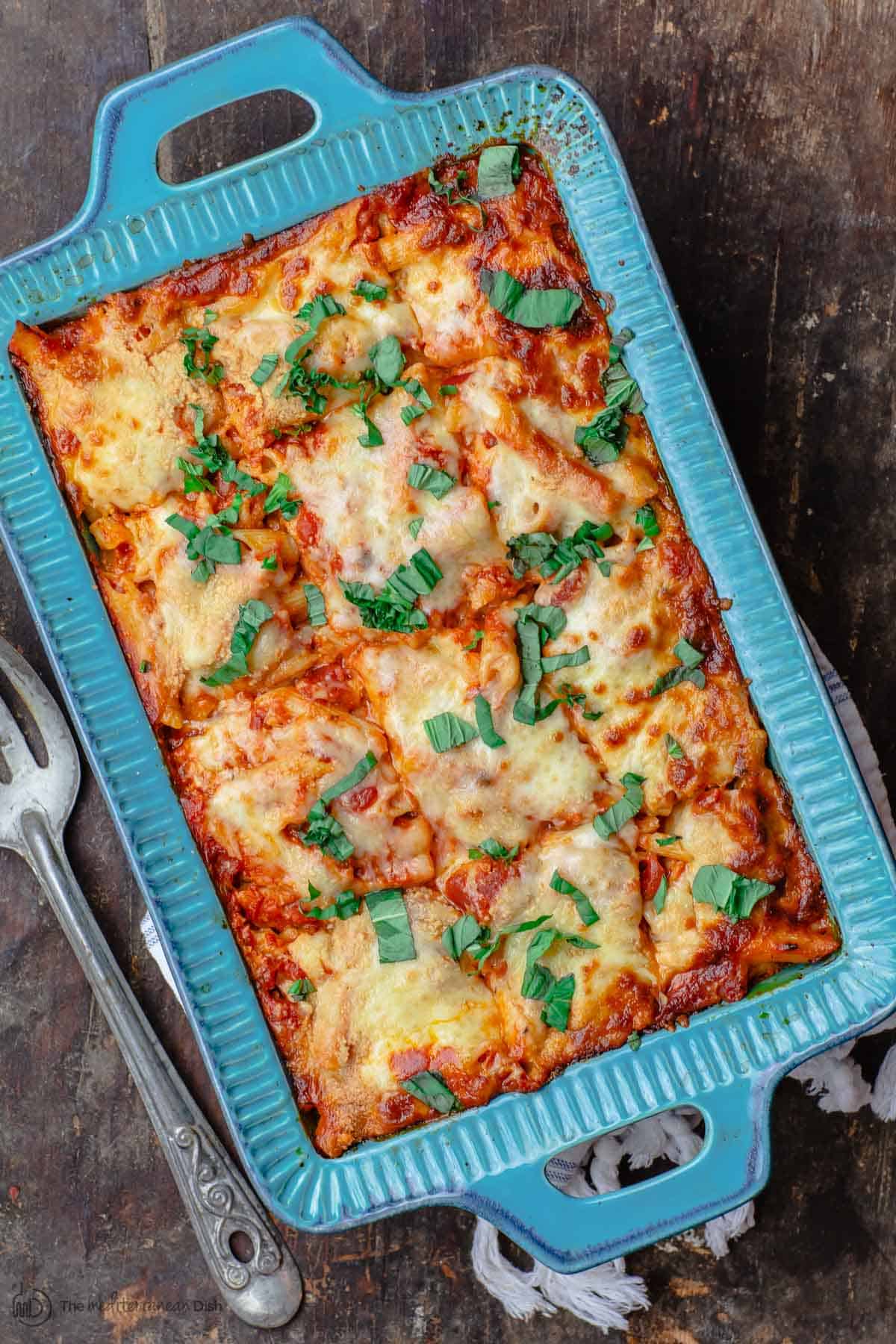 Vegetarian Baked Ziti in Blue Casserole Dish. Serving spoon on the side