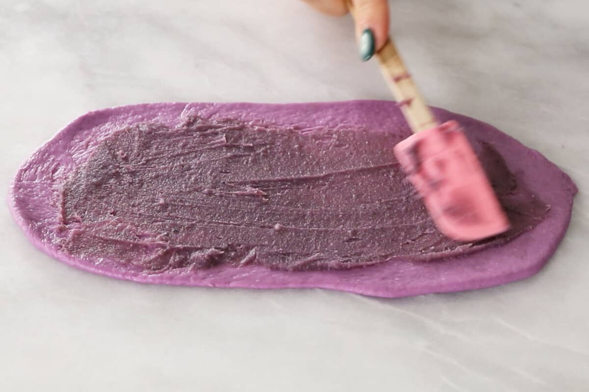 spreading ube halaya on ube ensaymada brioche bread dough