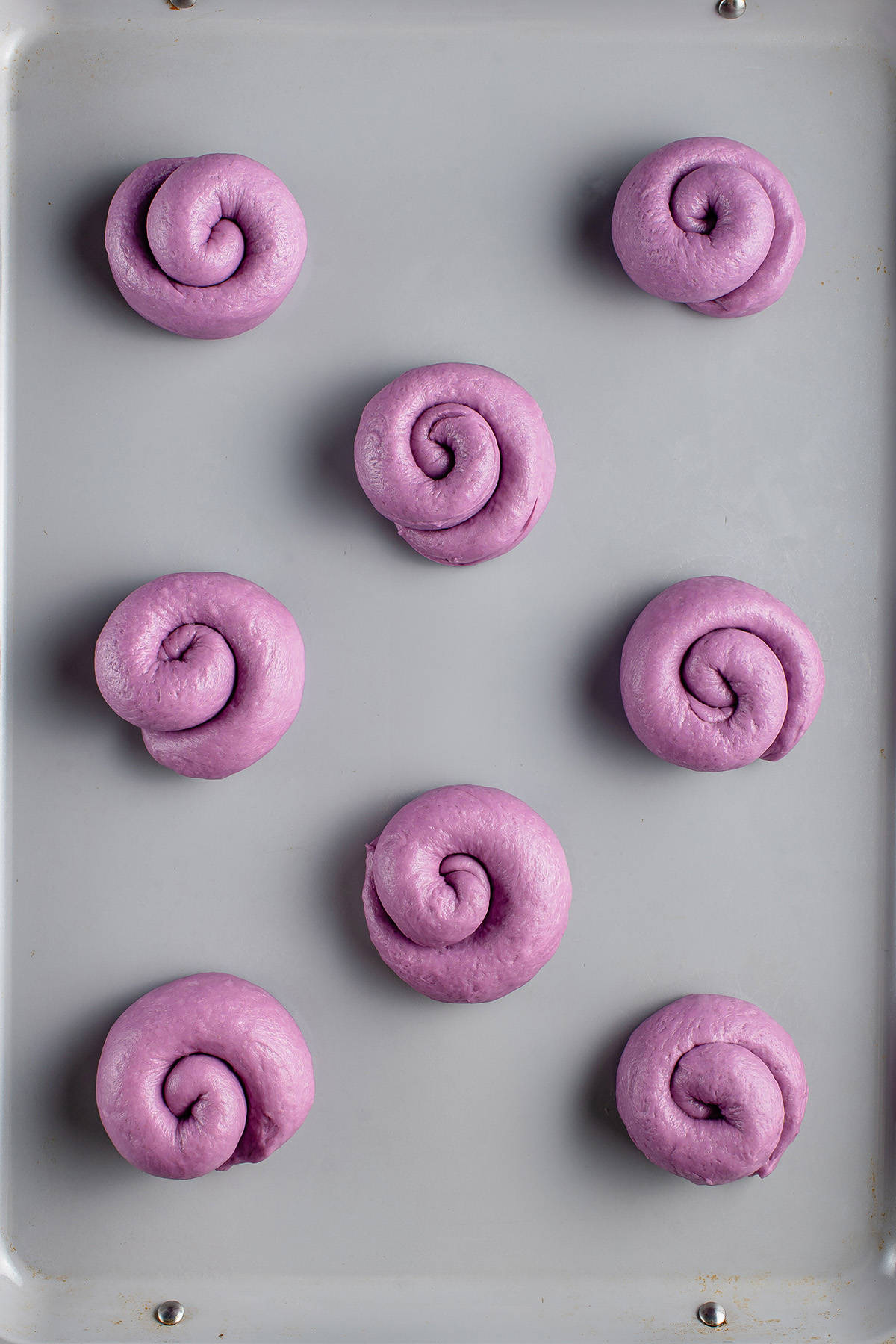 overhead photo of ube ensaymada dough on baking sheet before baking