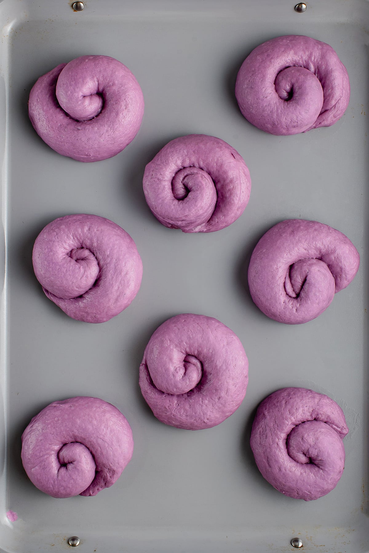 overhead photo of ube ensaymada dough on baking sheet after rising