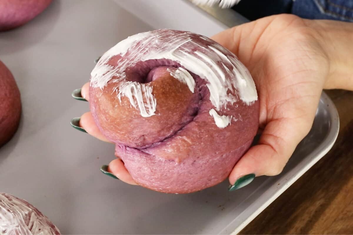 adding buttercream to Filipino ube ensaymada brioche bread