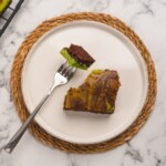 Homemade mint brownie served on a round white plate, with a fork holding a portion of the brownie.