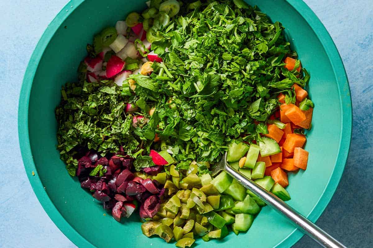 the ingredients for vegan chickpea salad in a mixing bowl before being mixed together with a fork.