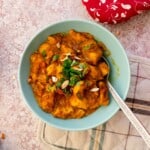 Keto chicken korma served in a bowl, garnished with green herbs and finely chopped nuts.