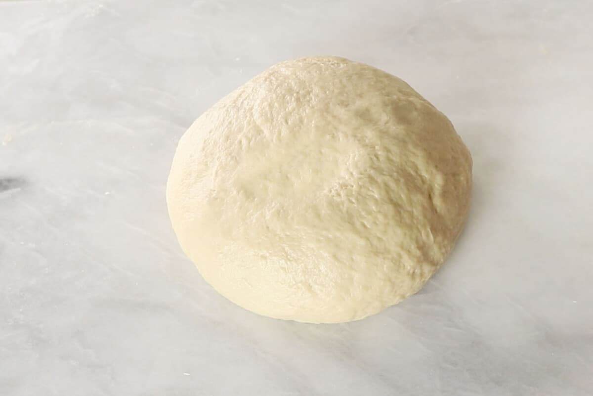 unbaked hawaiian roll dough after kneading on marble board