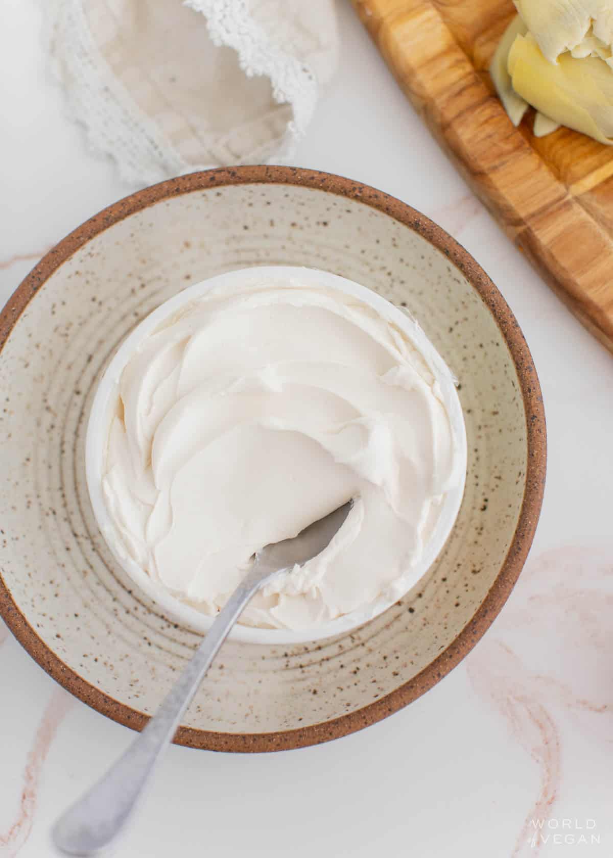 tub of dairy free vegan cream cheese in a container with a knife