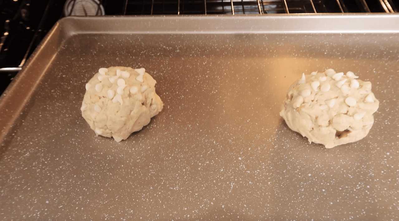 two macadamia nut cookies on a baking sheet going into the oven