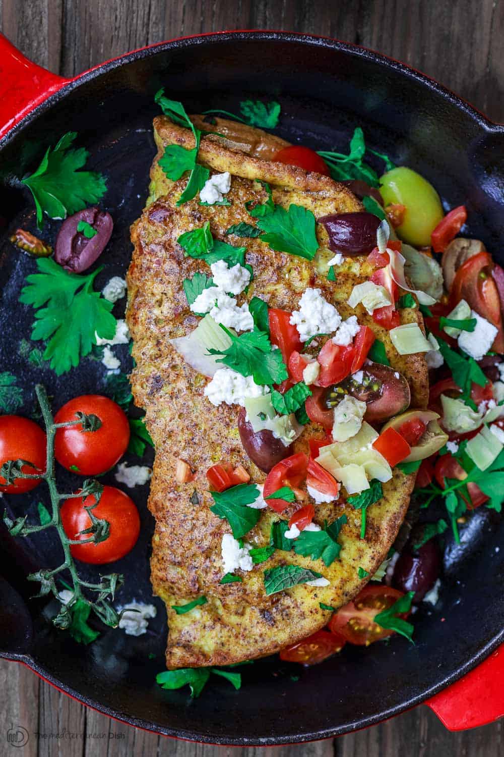 Loaded Mediterranean Omelette Recipe | The Mediterranean Dish. Perfectly-seasoned omelette loaded with fresh herbs and Mediterranean favorites like tomato, artichokes, feta and more. There is a secret ingredient that makes this omelette a little extra airy and fluffly! From TheMediterraneanDish.com