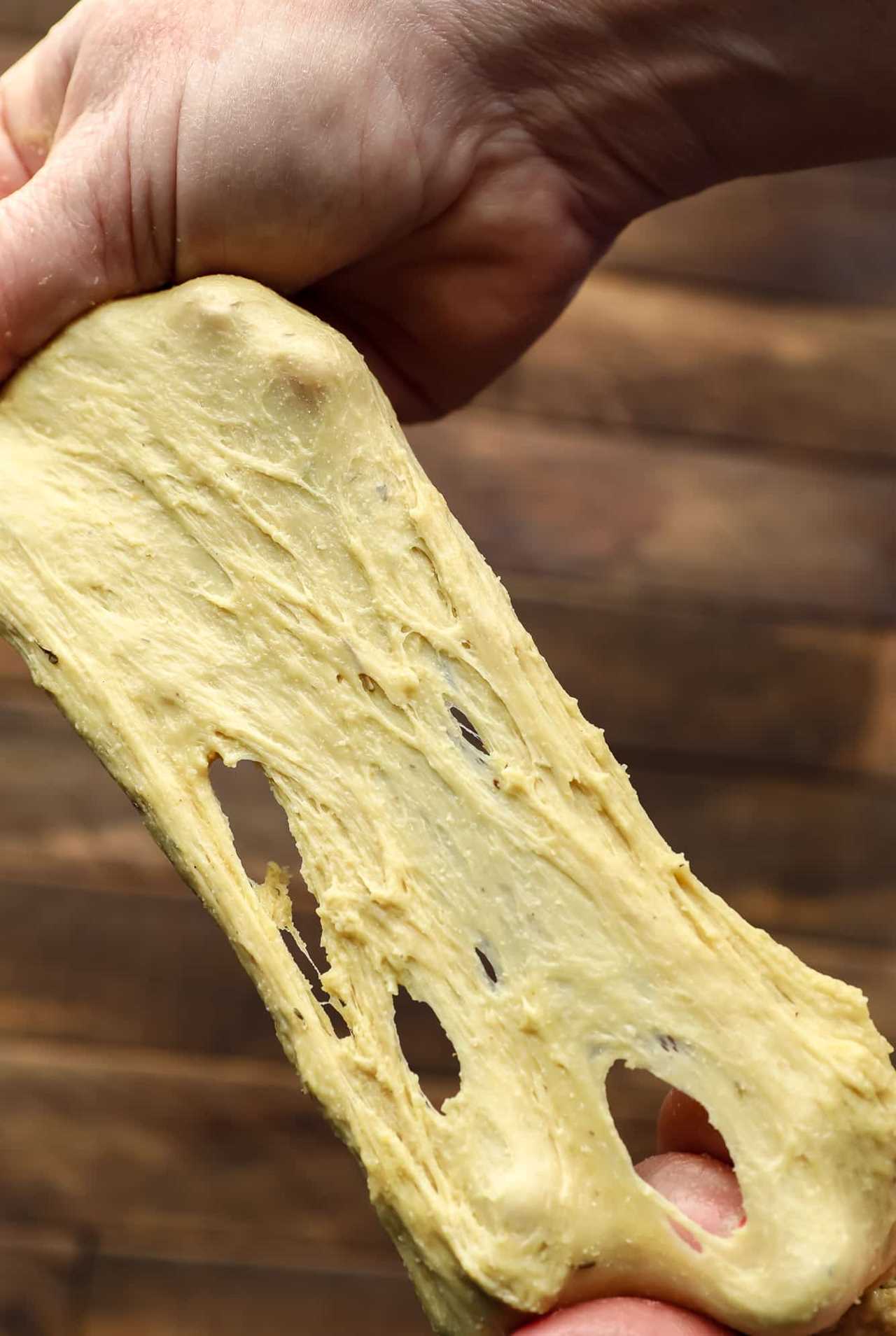 two hands stretching raw seitan dough.