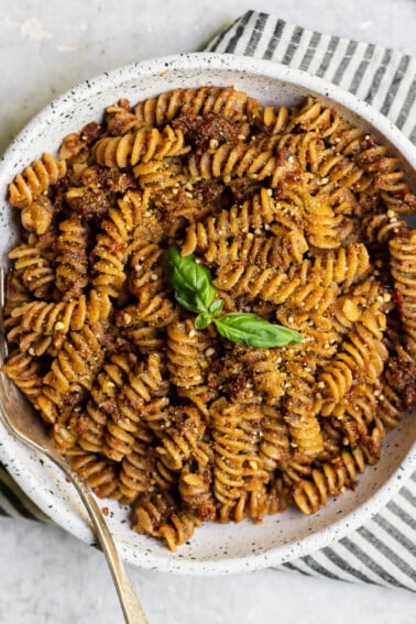 Bowl of vegan sun dried tomato pesto pasta with a towel food photography