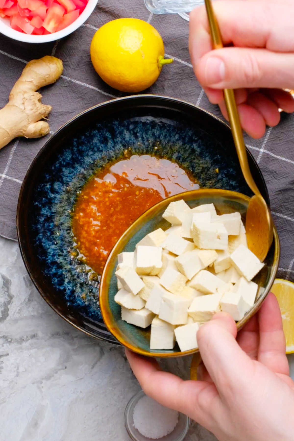 Cubed tofu being added to a bowl of marinade.